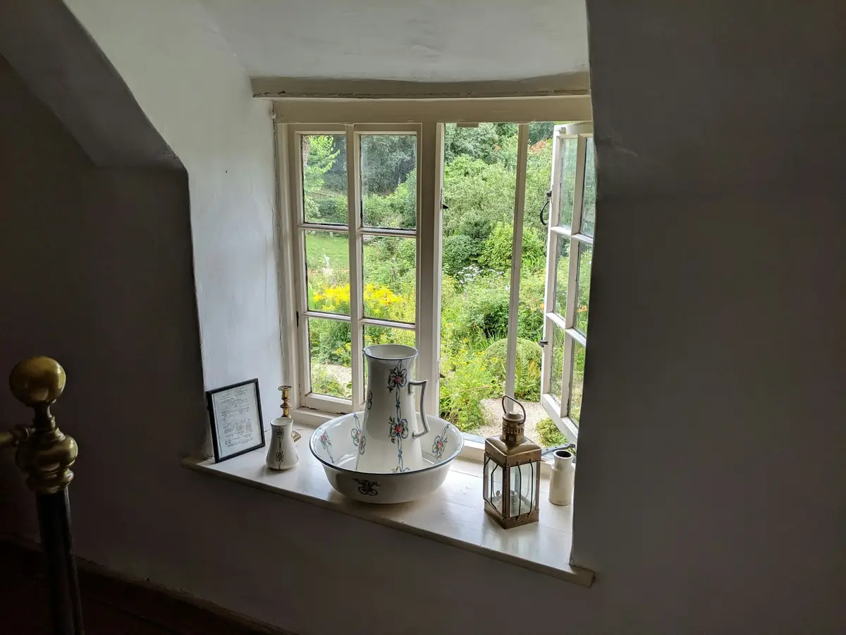 Timber casement window opened onto a cottage garden, seen from inside