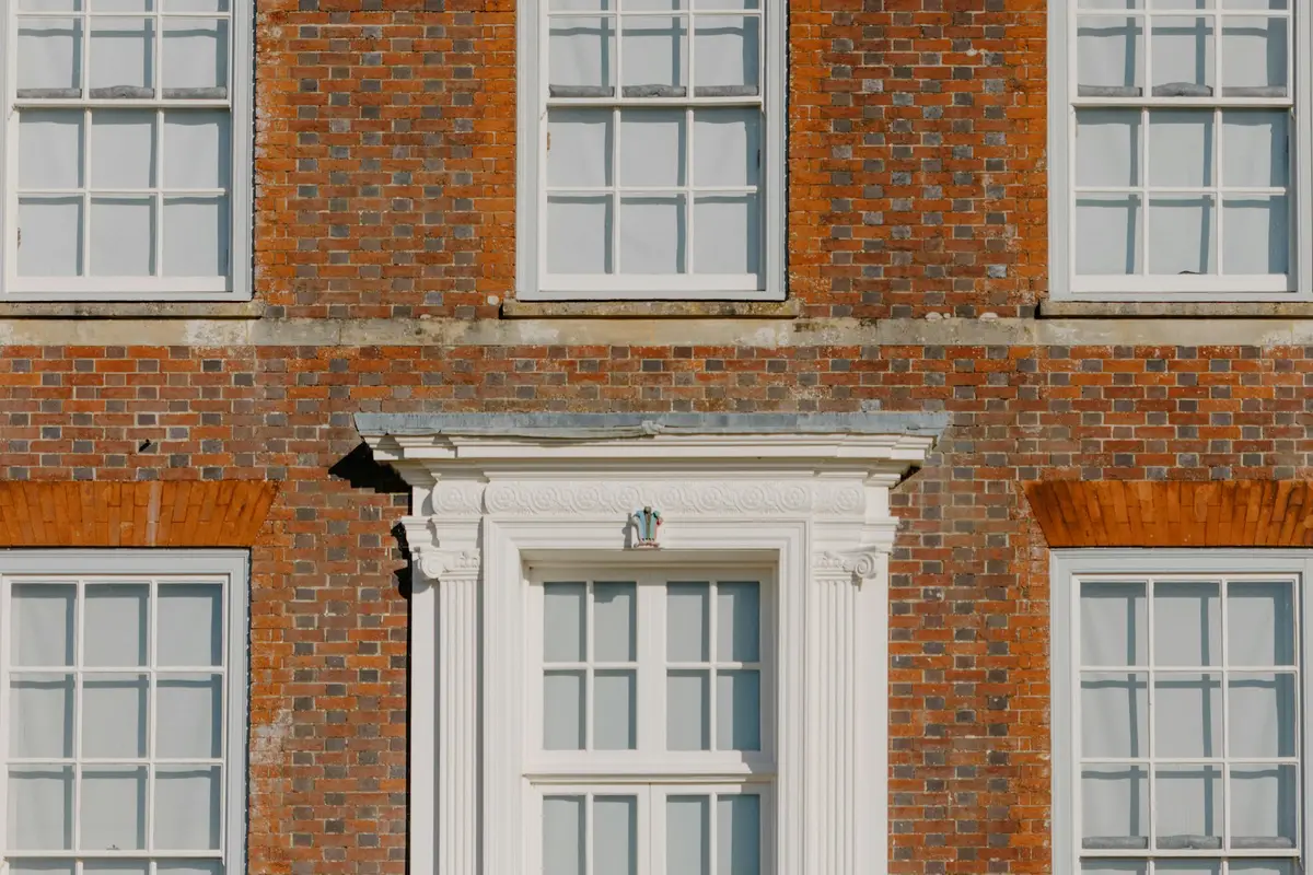 Georgian red-brick facade with six-over-six sash windows and a pedimented doorcase
