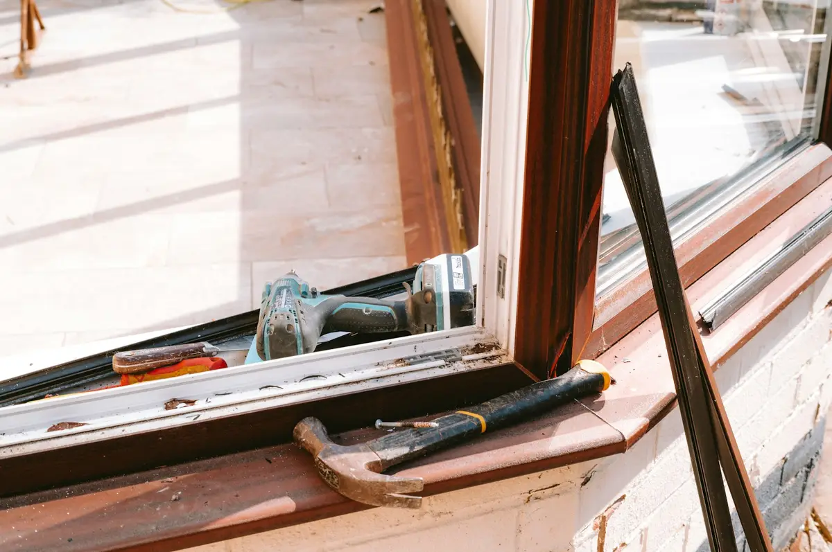 Old timber window opened up for repair, with a hammer and drill on the sill