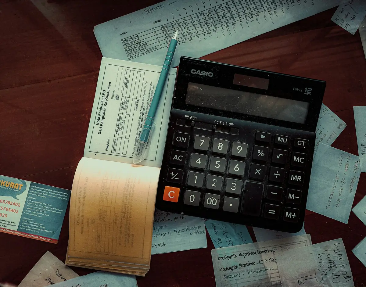 Calculator and pen on a table covered in household bills