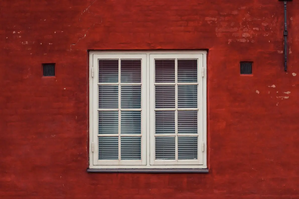 Single white casement window in a red brick wall