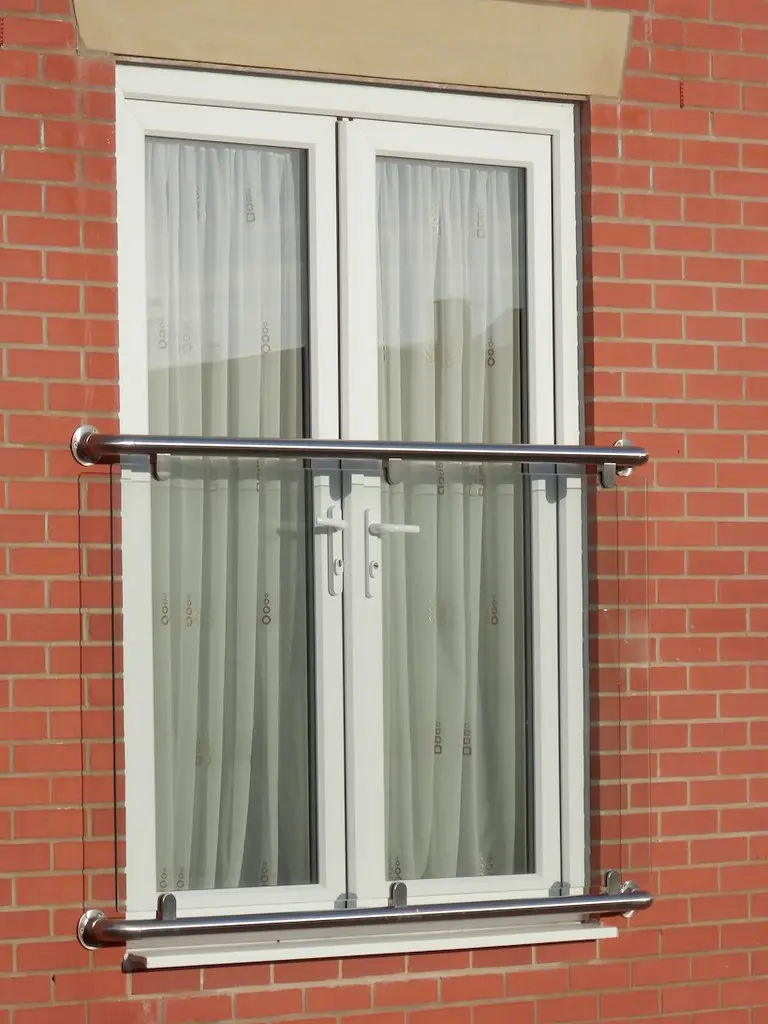 Brick flat with white French windows behind a glass Juliet balcony