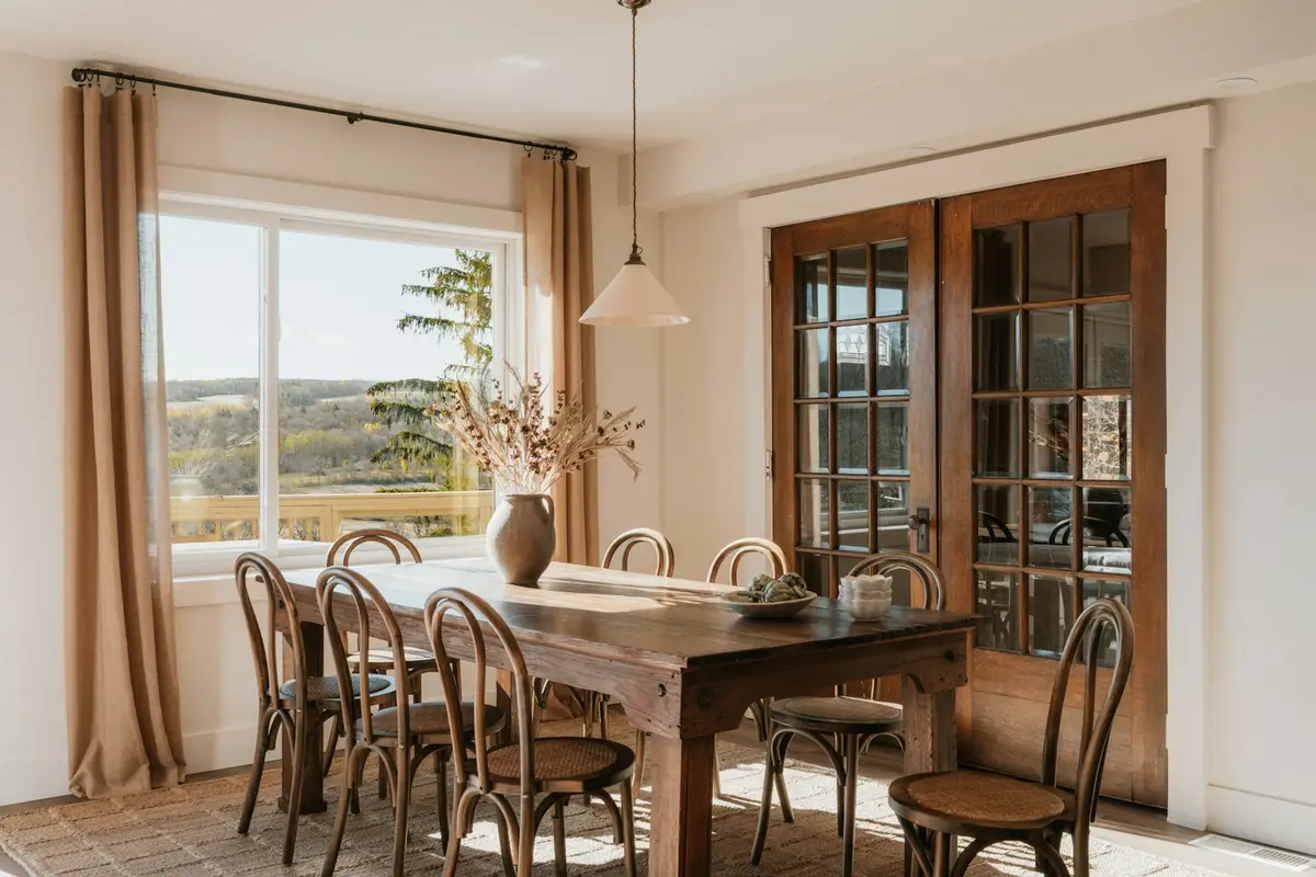 Dining table beside glazed timber French doors, seen from inside