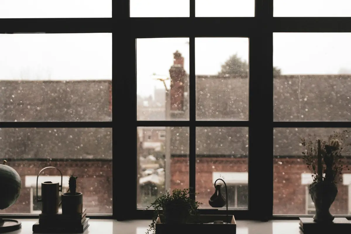 View from a dim room through a window over brick terraced houses