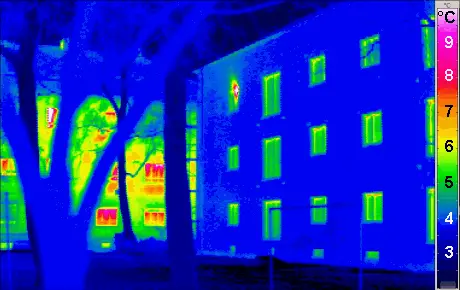 Thermal image comparing an insulated and an uninsulated building, with the windows showing warmer