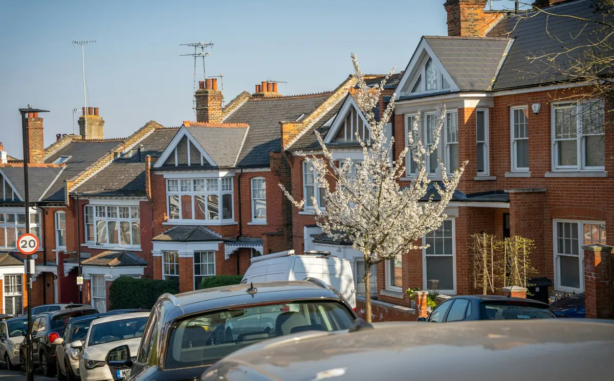 Row of red-brick semi-detached houses with bay windows and white window frames