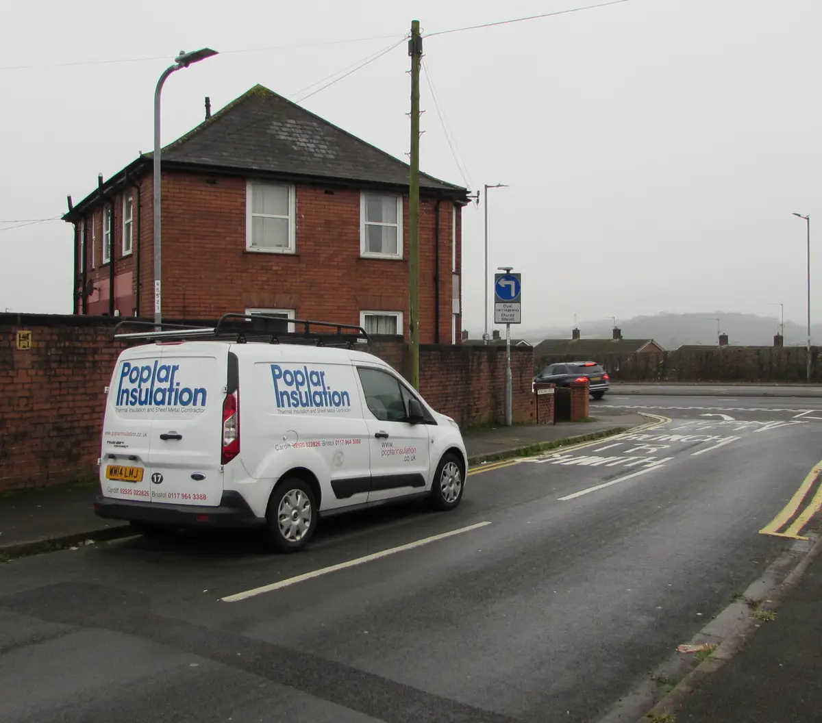 Insulation company van parked outside a brick house