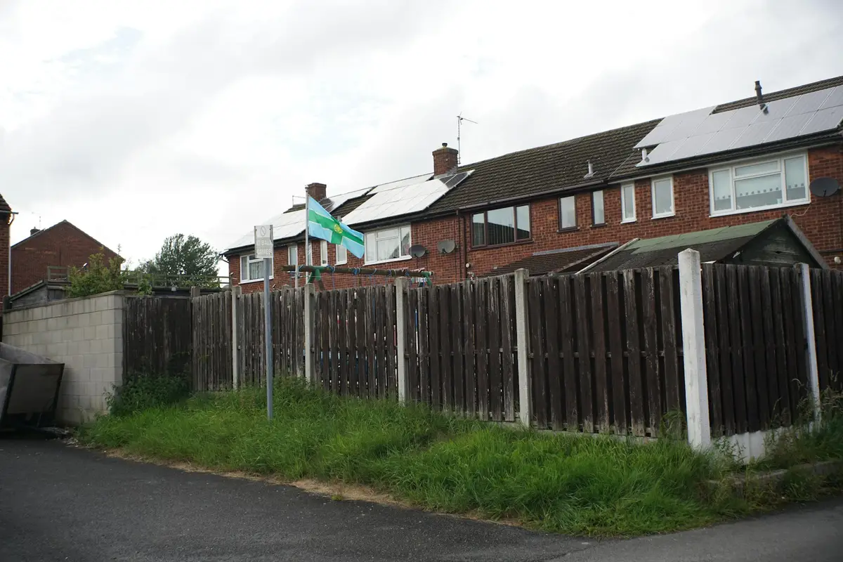 Row of brick houses with solar panels behind a garden fence